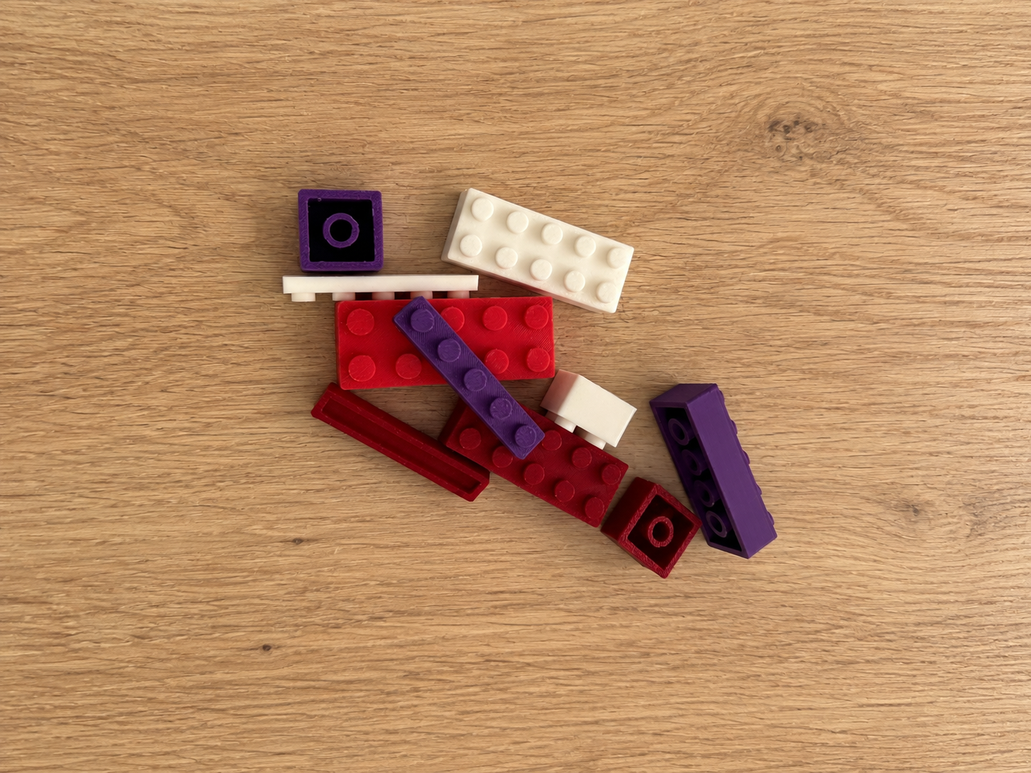 Real 3D-printed red, purple and white blocks on a wooden table