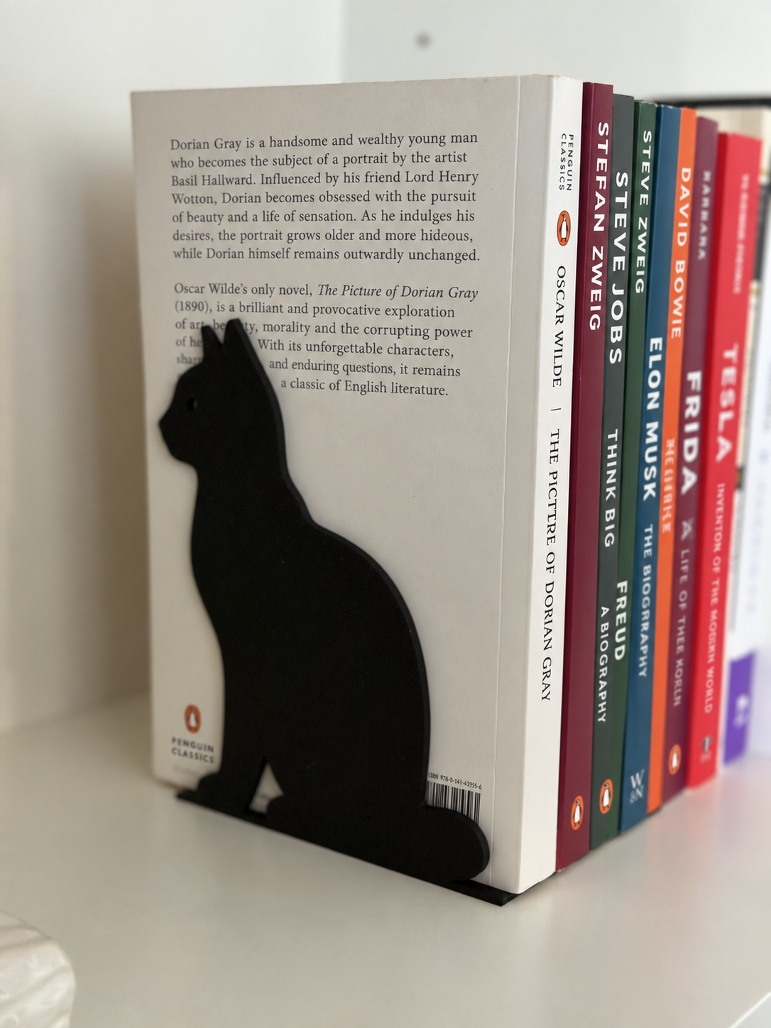 Black cat-shaped bookend supporting a row of books on a shelf