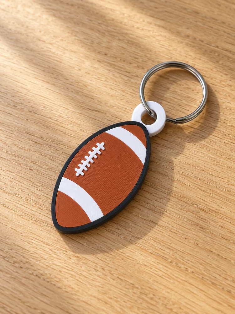 AI visualization of the matching printed football keychain with a silver ring threaded through its white attachment loop on an oak table